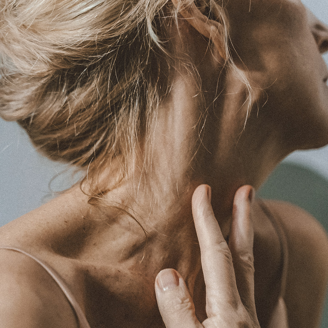 Nahaufnahme einer Person, die sanft mit der Hand ihren Hals berührt. Die Person hat helles Haar, das zu einem lockeren Knoten hochgebunden ist. Ihre Haut wirkt weich und sie trägt ein ärmelloses Oberteil, was einen intimen und ruhigen Moment einfängt. Nahaufnahme einer Person, die sanft mit der Hand ihren Hals berührt. Die Person hat helles Haar, das zu einem lockeren Knoten hochgebunden ist. Ihre Haut wirkt weich und sie trägt ein ärmelloses Oberteil, was einen intimen und ruhigen Moment einfängt.